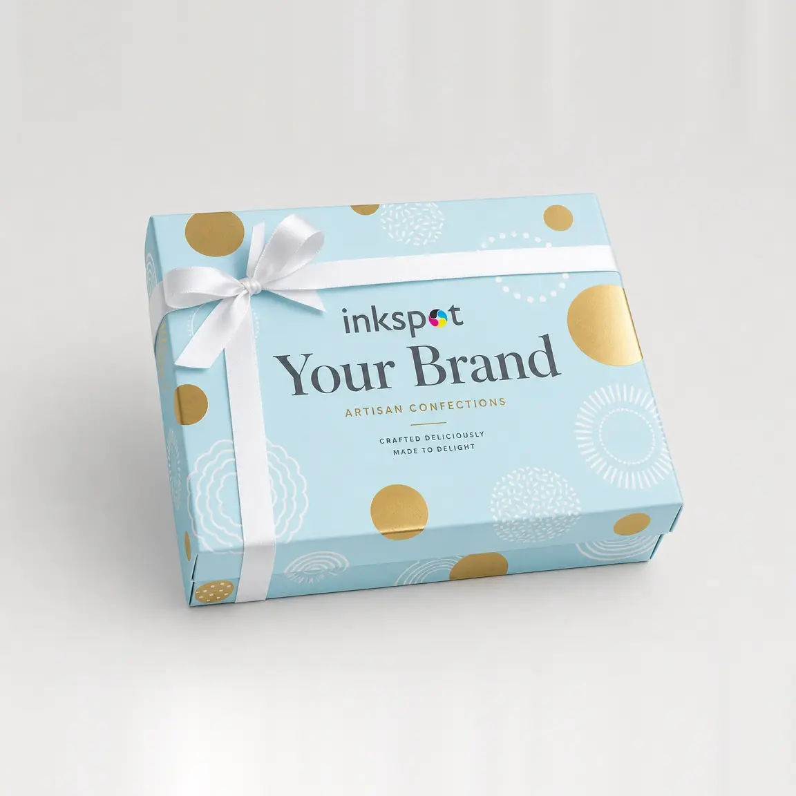 A pale blue confectionery gift box printed with gold foil sunbursts and tied with a white ribbon.