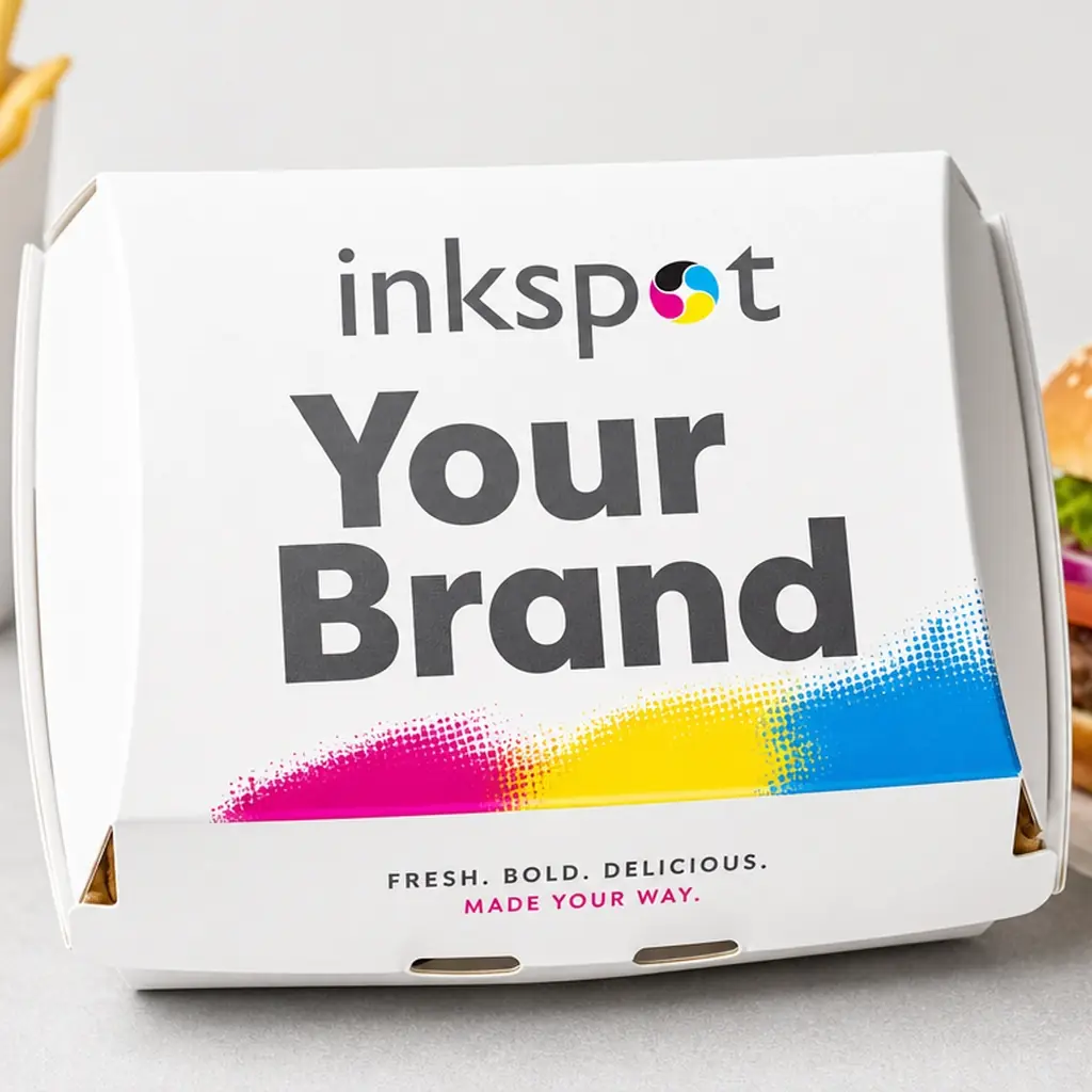 A printed clamshell burger box with chips and a burger beside it.