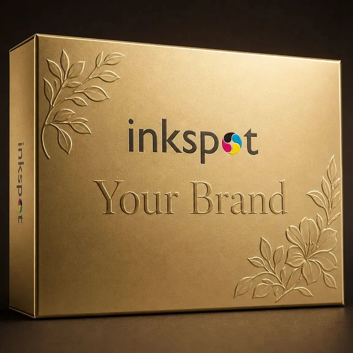 A gold metallic gift box with a blind embossed botanical pattern in the corners.